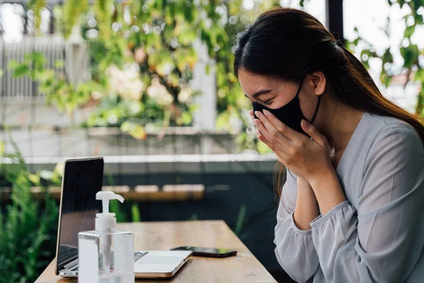 Uma mulher de negócios adulta jovem de 20 anos a espirrar com lenço de tecido. Freelancer feminino casual trabalhando com laptop ao ar livre com gel de álcool na mesa. Com espaço de cópia — Fotografia de Stock