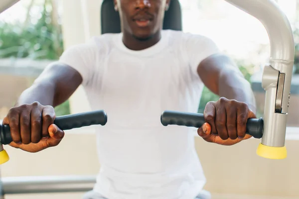 Афроамериканский спортсмен делает упражнения для грудных мышц на pec палубе машины во время тренировки в спортзале — стоковое фото