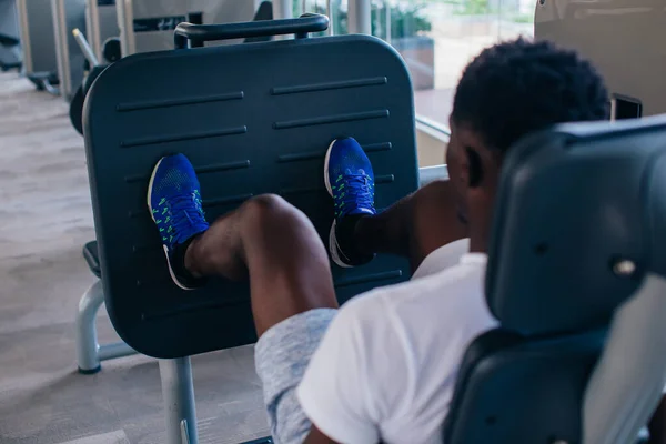 지금의 헬스클럽에서 건강 훈련을 받는 동안 다리에 힘을 주어 운동하고 있는 아프리카계 미국인의 뒷모습 — 스톡 사진