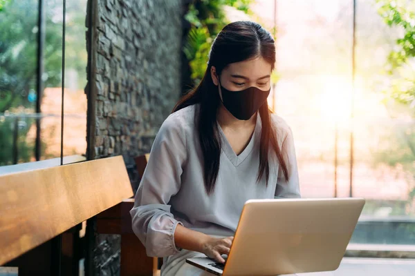 Ázsiai nő visel arc maszk kívül, miközben ül a laptopon — Stock Fotó