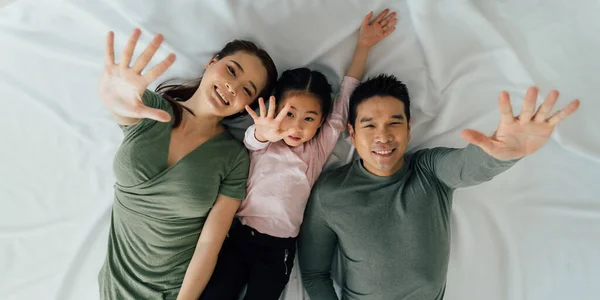 Retrato de alegre familia asiática tumbada y saludando —  Fotos de Stock