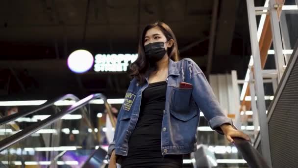 若いですアジアの女性身に着けています保護顔カバーダウンエスカレーターでショッピングモール — ストック動画
