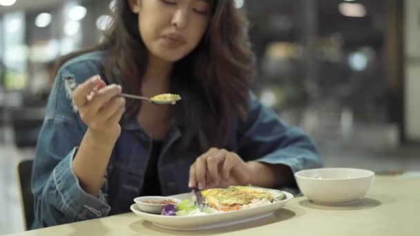 Mujer asiática joven sentada en la cafetería con mascarilla protectora mirando la cámara. Hermosa chica de Asia sentado en el restaurante cafetería — Vídeos de Stock