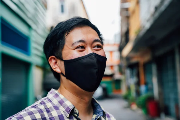 Retrato de um asiático sorrindo homem vestindo uma máscara facial na rua do bairro na Tailândia — Fotografia de Stock