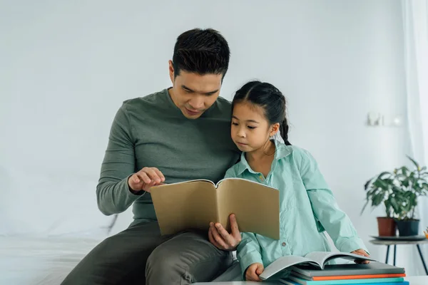 Asiático padre leyendo libro con hija —  Fotos de Stock