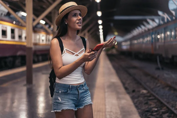 Young Mexican woman holding phone on train platform — Stock Photo, Image