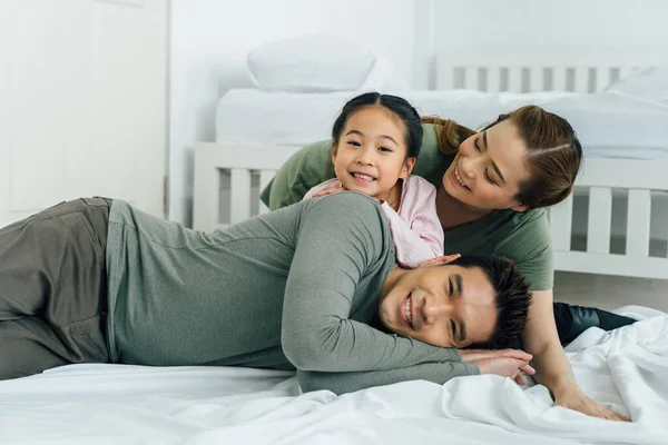 Ritratto di giovane famiglia asiatica sul letto sorridente — Foto Stock