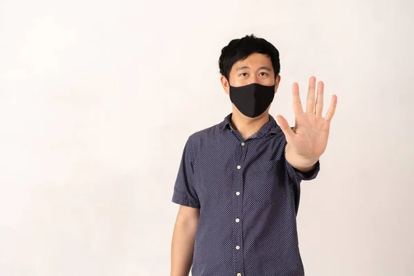 Aziatische man het dragen van gezicht masker met de hand palm verhoogd naar camera — Stockfoto