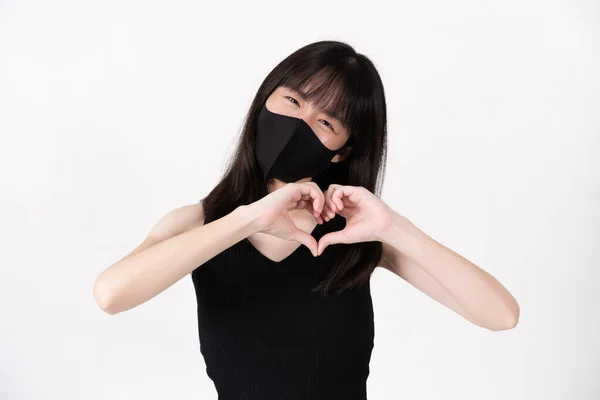 Korumalı maske takan Asyalı kadın elleriyle kalp şekli yapıyor. — Stok fotoğraf