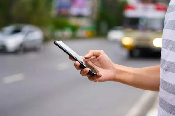 Hand of man using a mobile phone on the street. Use of transportation app — Stock Photo, Image
