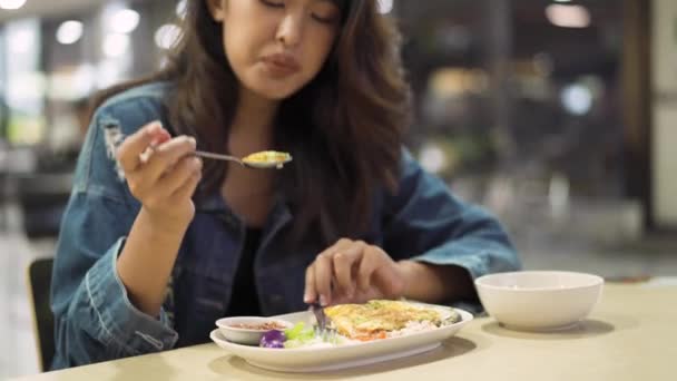Mujer asiática joven sentada en la cafetería comiendo comida. Hermosa chica de Asia cenando sola — Vídeos de Stock
