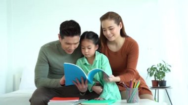 Asyalı baba ve anne kızlarıyla kitap okuyor.