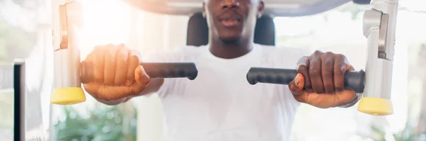 Афроамериканский спортсмен делает упражнения для грудных мышц на pec палубе машины во время тренировки в спортзале — стоковое фото