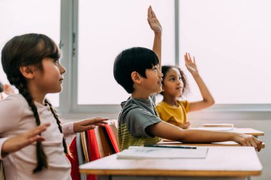 Asyalı ilköğretim öğrencisi çocuk Q ve A sınıfında el kaldırdı. İlköğretim okulunda ilköğretim çağında çeşitli anaokulu öğrencileri grubu.