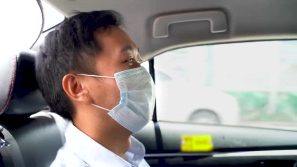 Asian Businessman siedzi na tylnym siedzeniu taksówki w masce ochronnej twarzy podczas pandemii, w ruchu, podróży służbowej, bezpieczeństwa — Wideo stockowe