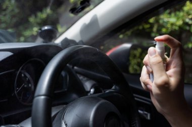 Arabanın direksiyonunu dezenfekte etmek için alkol spreyi kullanan insan eli. Püskürtme Coronavirus Covid-19 enfeksiyonunu önler