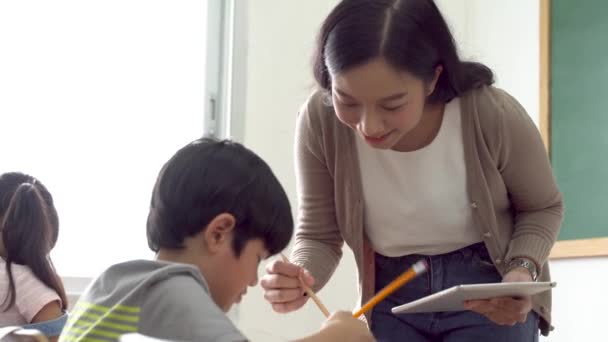 Azjatycki nauczyciel korzystający z urządzenia cyfrowego z dziećmi w klasie w szkole, technologii, uczenia się, rozwoju — Wideo stockowe