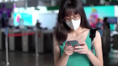 Koronavirüs salgını sırasında metroda seyahat etmek için koruyucu yüz maskesi takan Asyalı kadın, yıkanabilir maske, hastalığın yayılmasını engellemek, akıllı telefondan mesaj atmak...