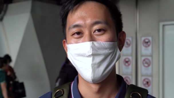 Hombre asiático con mascarilla protectora cubriendo para viajar en metro durante la pandemia de coronavirus, detener la propagación de la enfermedad en el transporte público, mirando a la cámara. — Vídeos de Stock