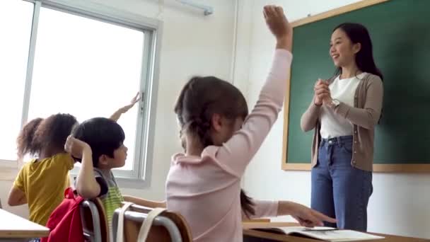Profesor de escuela asiática con estudiantes levantando las manos. Mujer joven trabajando en la escuela con el brazo levantado, los niños de la escuela poniendo sus manos para responder a la pregunta, entusiasmo, impaciente, disfrute — Vídeos de Stock