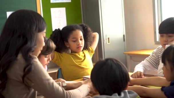 Asian school teacher assisting students in classroom — Stock Video