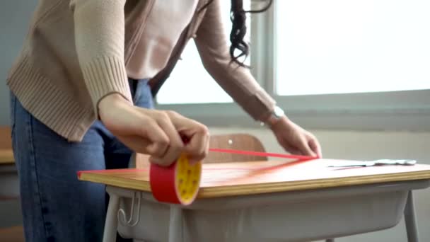 초등 학교 교실 책상 위에 빨간 접착제 테이프를 부착 한 여교사의 새로운 일반 개념인 Covid19 교육 건물에서 사회적 거리 측정 정책을 유지하기 위해 — 비디오