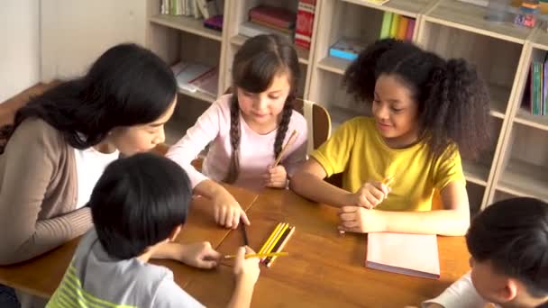 Asian school teacher conducting a group study with multiethnic students in classroom — Stock Video