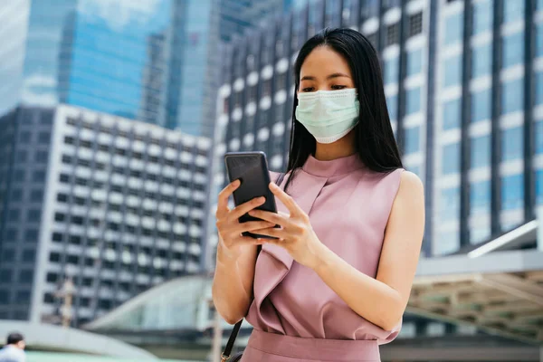 Asian businesswoman wearing face mask using smart phone