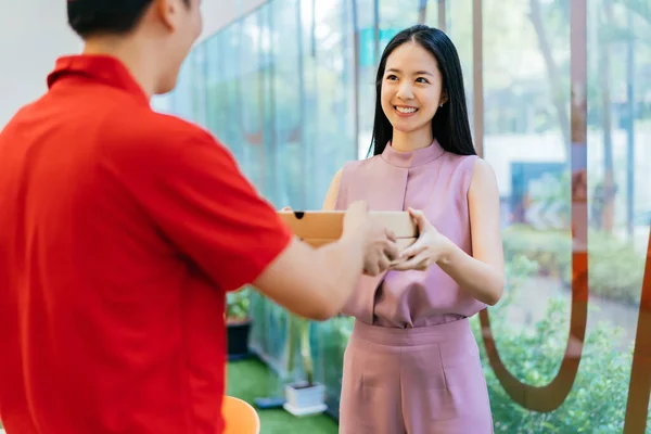 Asian businesswoman receiving pizza delivery at office