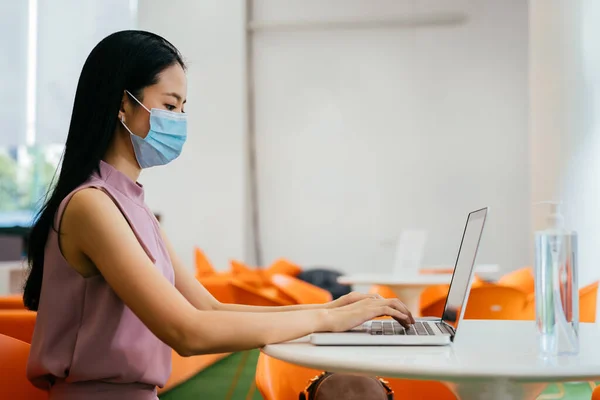 Mulher de negócios asiática usando máscara facial usando laptop no escritório — Fotografia de Stock