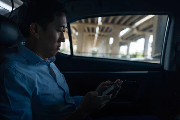 Empresário alegre sentado no banco de trás do carro conversando no telefone — Fotografia de Stock