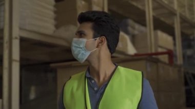 Yüz maskesi takan genç Hintli fabrika işçisi çalışmadan önce vücut ısısını kızılötesi termometreyle ölçüyor. Coronavirus salgınında iş yerinde güvenlik önlemi