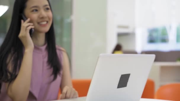 Mulher de negócios asiática alegre no telefonema sozinho em edifícios de escritórios modernos. Feliz negócio sorridente startup empresária usando laptop — Vídeo de Stock