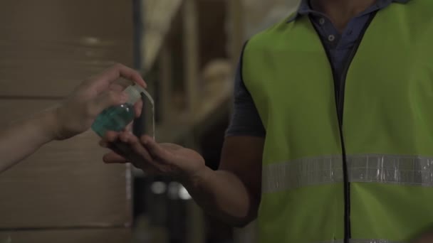 Vystřižený inženýr pracovník pomocí alkoholu na ruční dezinfekci gel pro mytí rukou při práci v továrně skladu v masce obličeje. Udržování hygieny rukou zabránit Coronavirus Covid 19 pandemický virus šíří — Stock video