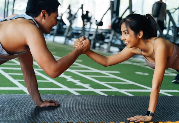 Casal sorrindo saudável do homem e da mulher que dá cinco elevados a se ao empurrar acima no gym da aptidão. Asiático desportivo pessoas trabalhando fora juntos — Fotografia de Stock