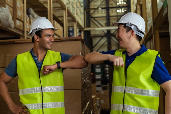 Mannelijke magazijn werknemers doen elleboog bump werken in de logistieke industrie indoor. Vrienden begroeten en schudden met ellebogen als nieuw normaal — Stockfoto