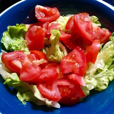 Koyu bir masa arka plan üzerinde taze domates ve marul salatası Vegan lacivert plaka