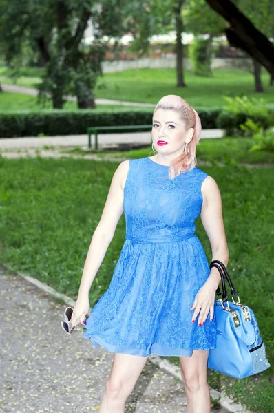 女人与一个蓝色的钱包在一个多风的公园 美丽充满活力的女人的主题 — 图库照片