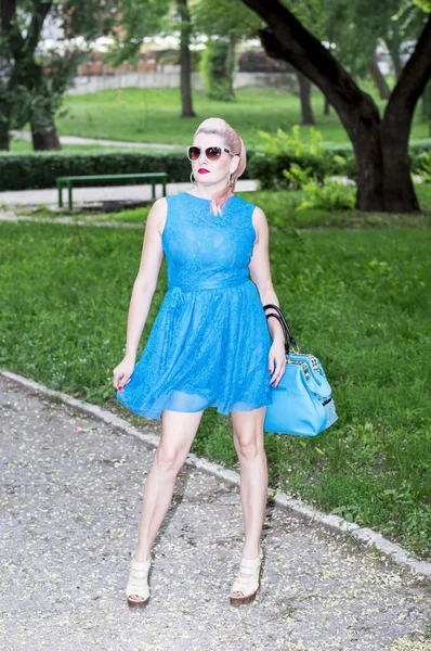 Mavili kadın parkta güzel canlı kadınlar temanın bir çanta ile