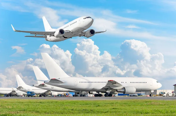 Row of passenger aircraft, airplane parked on service before departure. at the airport, other plane push back tow. One take off from the runway in the sky