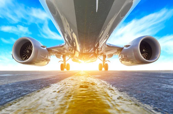 Airplane in the parking lot of the airport apron, bottom view hdr of engines, fuselage and wings. Against the background of the sky clouds and bright sunlight