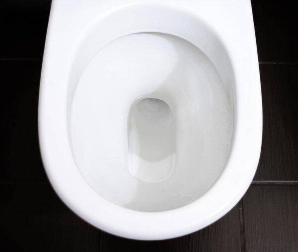 White toilet bowl in the bathroom, and flushing the water