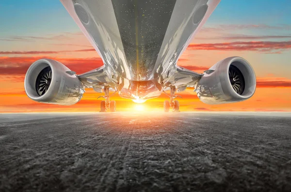 Airplane in the parking lot of the airport apron, bottom view- engines, fuselage and wings. Background of the sky sunset sky clouds