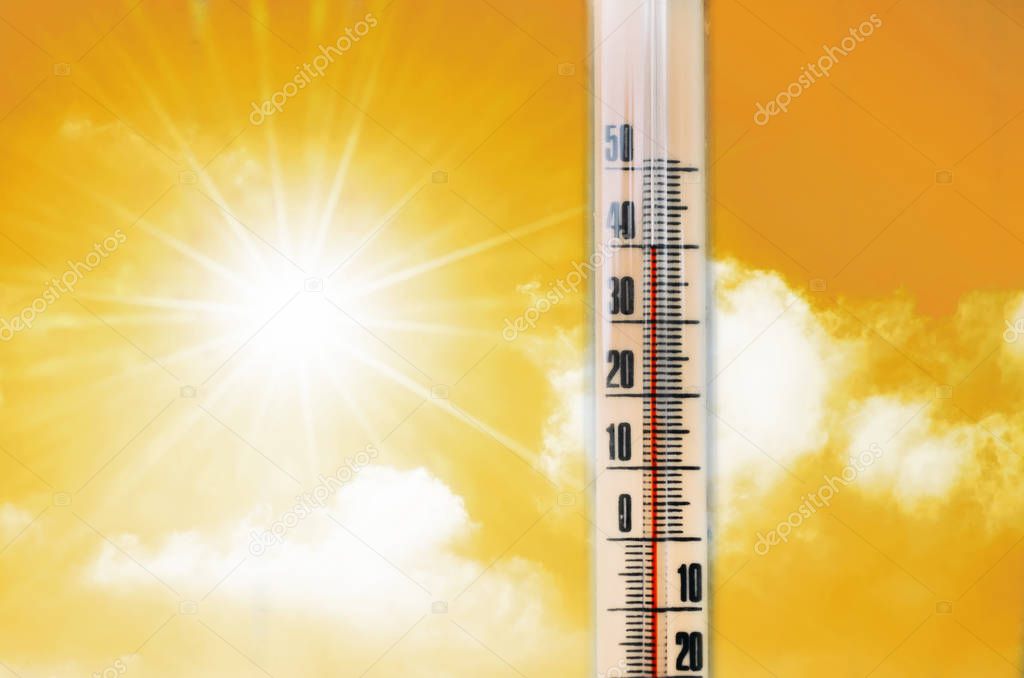 Thermometer against the background of an orange yellow hot glow of clouds and sun, concept of hot weather. Above 40 degrees Celsius