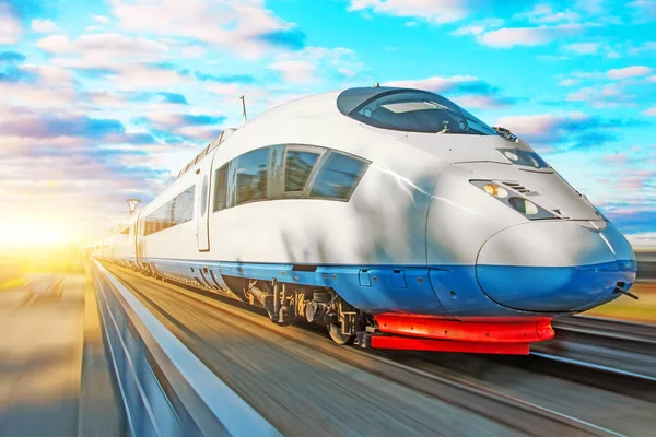 High speed train passenger locomotive in motion at the railway station at sunset with a beautiful picturesque sky. — Stock Photo, Image