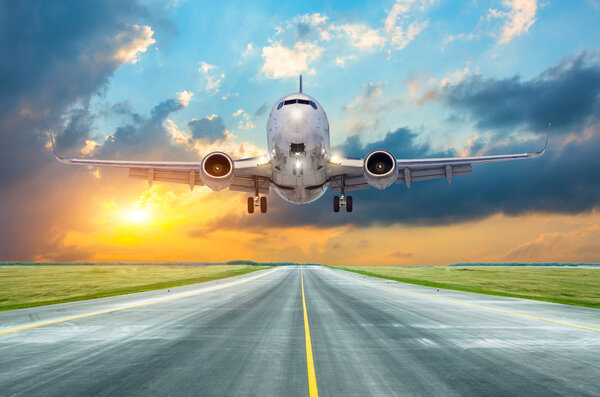 Посадка пассажирского самолета на закате на взлетно-посадочной полосе
