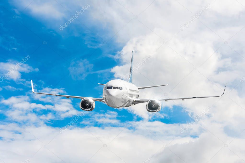Passenger airplane flying at flight level high in the sky above the clouds and blue sky