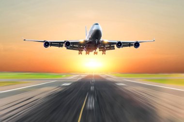 Parlak kırmızı günbatımı sırasında akşamları bir piste iniş yolcu uçak