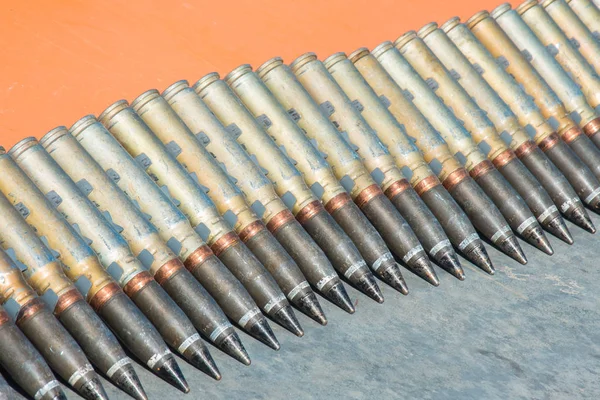 Number of cartridges from machine gun folded in a row on a orange background
