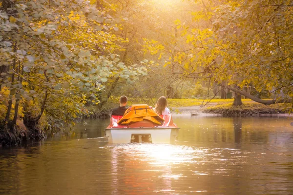 Couple in love in a catamaran, water bike in a park in autumn, sunset